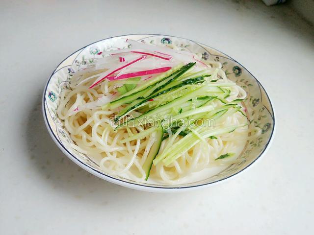 取适量凉面在盘子里，再铺上适量黄瓜丝和水萝卜丝。
