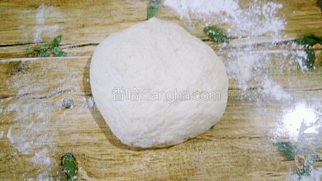 案板洒适量的干面粉  把发酵好的面团排下气  用手揉下   