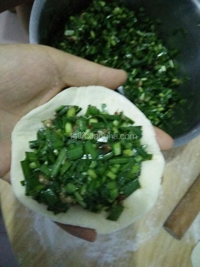 拿起一个面皮中间放入韭菜馅儿。