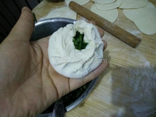 左手拖住底部，右手捏折转着成圆形的包子