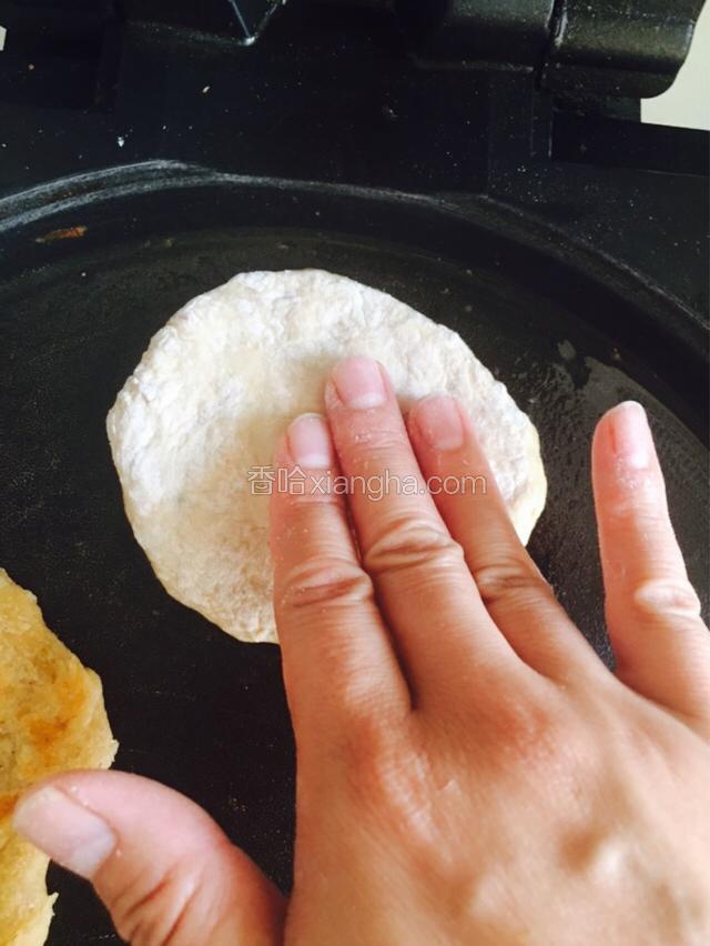 把鱼饼放入电饼铛内，用手按扁，每一个都这样做。