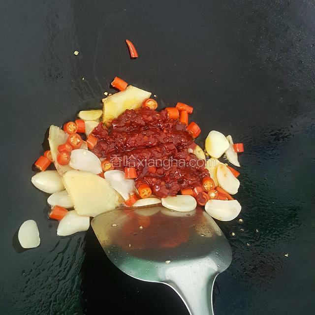 热油锅，油有些许冒烟的时候就先倒入姜片蒜片和小米椒，炒制出香气了再加入1勺豆瓣酱翻炒