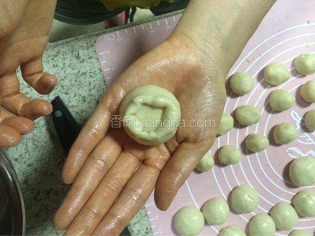 把油皮用手按成圆片（不用太大），油酥剂子放在油皮中间，用虎口一点一点把口收住