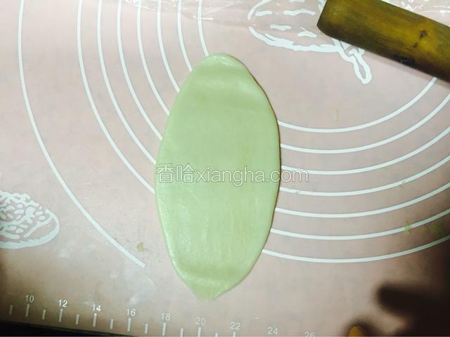 把上一步得到的擀成如图片的样子，用擀面杖擀两三下擀成，不用太长，15公分以内即可，宽度约5公分左右
