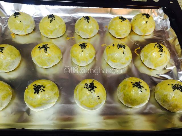每个蛋黄酥上面刷两层蛋黄液，这样烤出来颜色会好看些，再在顶部洒少许黑芝麻
