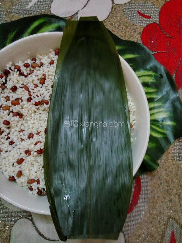 把粽叶底部剪掉，折成漏斗状，下端不要有空隙，以防煮的时候漏米