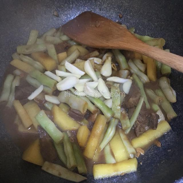 肉上色后加入开水，放入豆角，土豆，蒜片