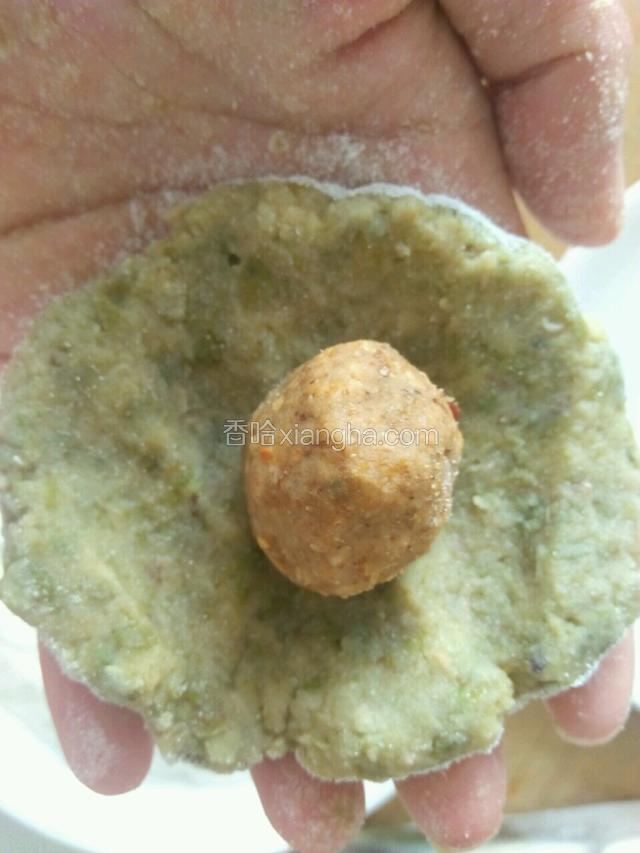 拿起压扁的绿豆饼将馅放中间，攥紧再搓成团