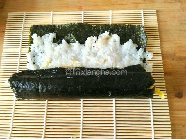 双手用力用卷帘将紫菜卷起来，这是卷到一半的紫菜卷。