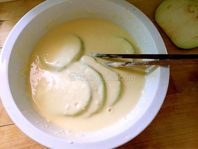 准备一个盆，在盆里把面糊糊调好：面粉、鸡蛋、盐和鸡粉，加适量的水，不能太稀也不能太稠，把粘上干面粉的茄片放到盆里，两面都粘上面糊糊。