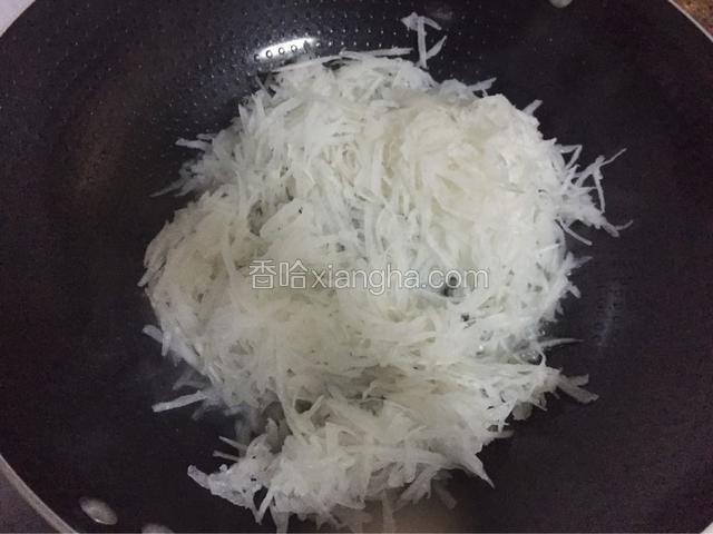 锅中倒入适量的油烧热后放入白萝卜丝，翻炒至断生