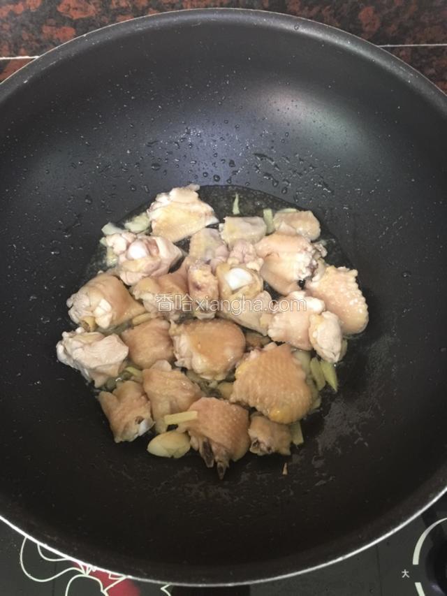 文火爆香姜蒜，待蒜末微黄时倒入鸡翅，改大火翻炒至微微发黄。