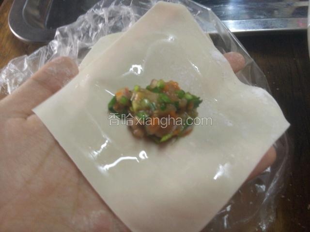 将肉馅放在云吞皮中间，四周抹上少量水