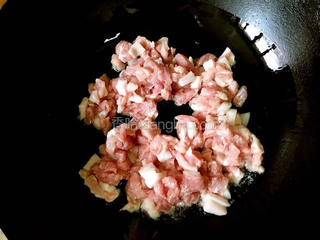 油锅内放入适量油，油热后加入腌制好的肉丁翻炒片刻。