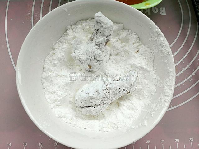 去掉葱姜蒜片，用纸巾擦下鸡翅表面少许汤汁，在把蒸熟鸡翅放入淀粉裹匀