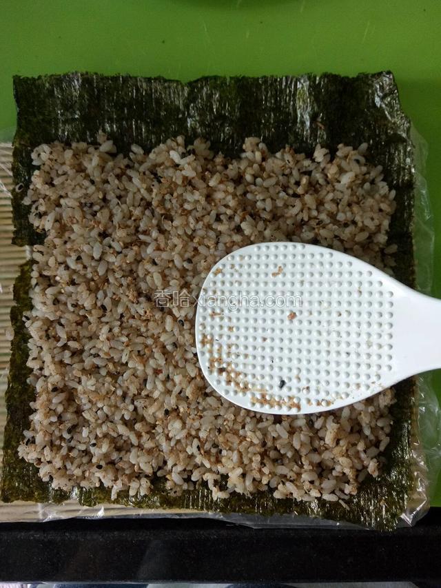 铺上拌好的米饭，用饭勺压实（紫菜上部留空3厘米，沾少许开水，便于收边，其余三边各留空1厘米，以免米饭溜出来）