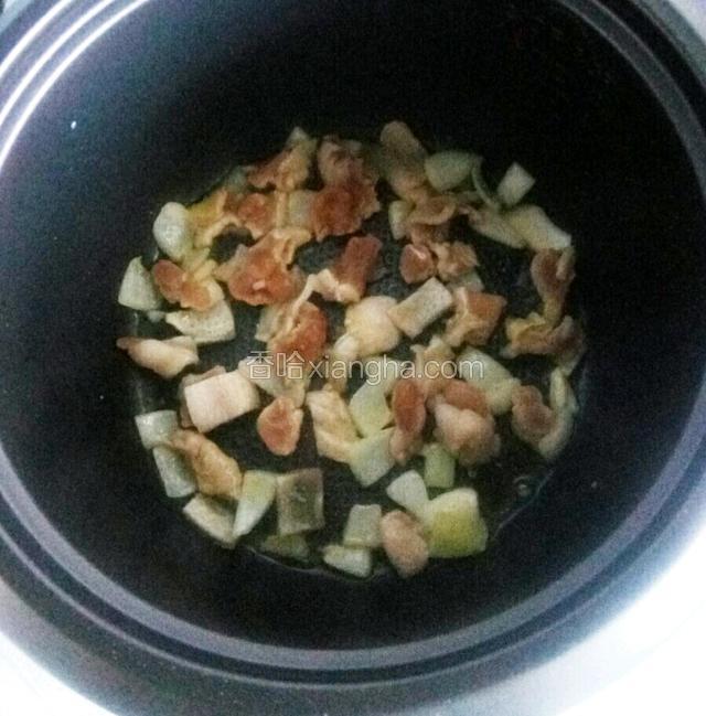 将腌制好的肉片和孜然放入电饭锅中用木制铲子不停翻面。