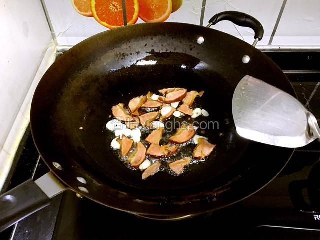 锅中加入适量油，烧热后爆香蒜片，倒入腊肉炒香。