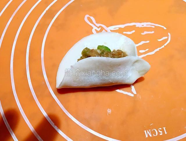 用食指从饺子皮的一头往里推一下，然后捏一个褶子