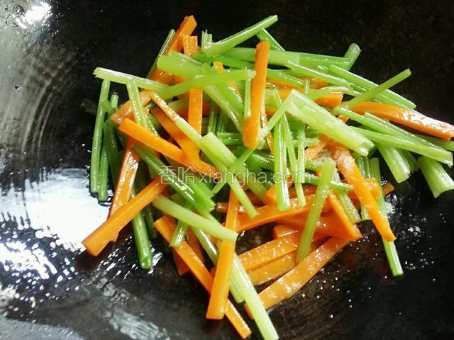 接着把焯过水的芹菜和胡萝卜下锅，放少许的盐，大火翻炒几下