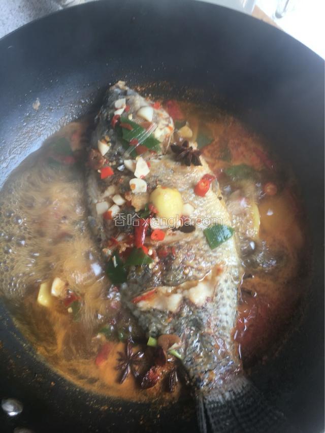 把葱白撒入四周，加八角入味，用小勺盛汤汁浇变鱼身，盖锅盖焖5分钟