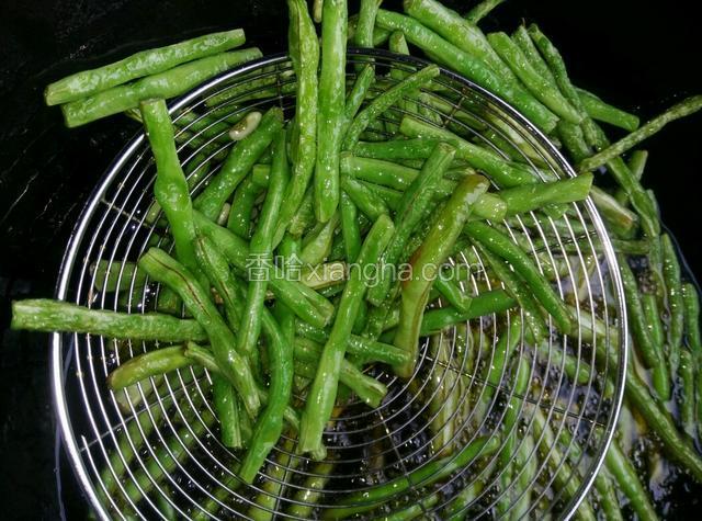 等到豇豆成虎皮状就可以用漏勺把它沥起来了，油沥干。装容器里待用。