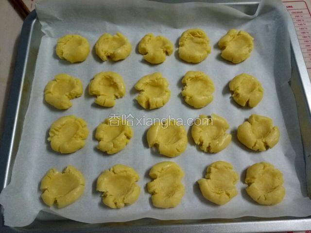 烤盘上铺油纸，把滚好的小圆球放在烤盘上，用大拇指在中间按扁，让它出现自然裂纹。