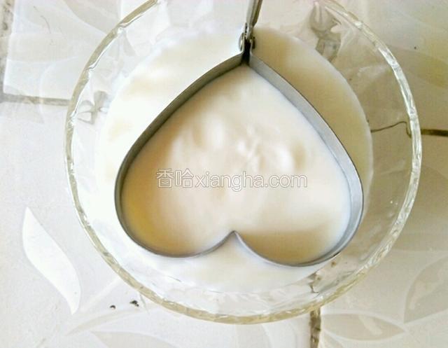 取出酸奶，倒入玻璃容器，然后用手心形模具放入酸奶表面。
