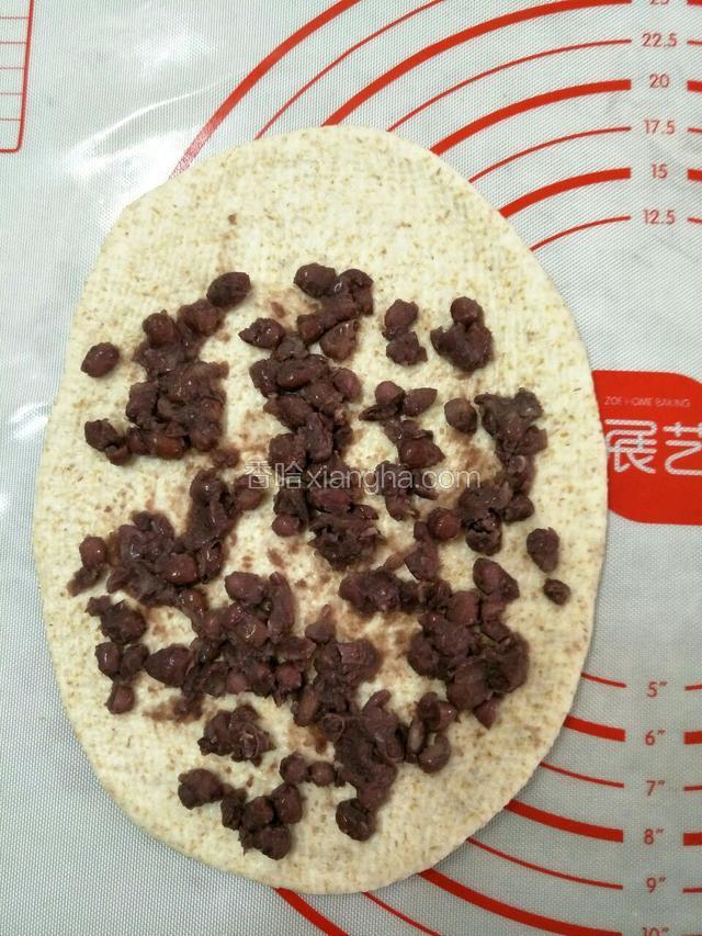 松弛好了，开始整形，每个小面团再滚圆之后，取一个面团擀成椭圆形，均匀的铺上事先用元真糖煮好的益糖蜜红豆。(煮法可以参考之前发过的益糖蜜红豆食谱。)