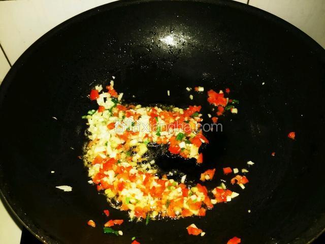 另起热锅，倒适量花生油，油热下刚刚切碎的葱花，蒜末，柿子椒碎，大火翻炒。