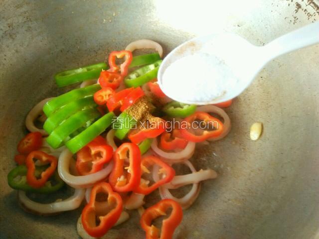鱿鱼圈炒好后倒入青，红辣椒圈，加入盐，鸡精粉，孜然粉各半勺，翻炒至辣椒断生即可出锅。