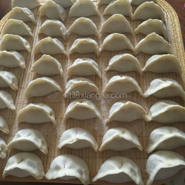 买现成的饺子皮，包好饺子整齐码放在竹帘上。