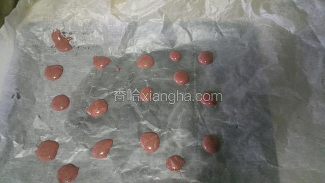 取一小勺面糊加入少许红曲粉拌匀，烤盘中放一张大的油纸，烤箱预热150度，先将红色面糊以小圆点状放在油纸上入烤箱烤3分钟
