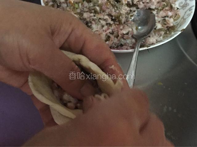 左手大拇指轻轻按压馅儿，右手把皮旋转，捏在一起