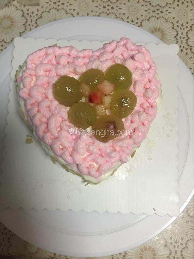 然后在蛋糕外围粘上杏仁片，爱心中间放上几颗葡萄和水蜜桃粒