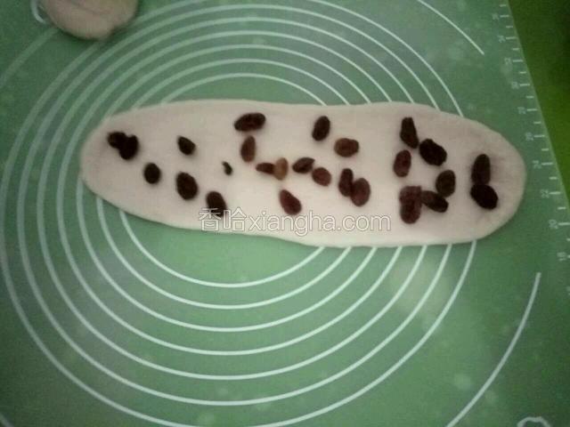 擀至长舌状，撒上泡好的葡萄干。