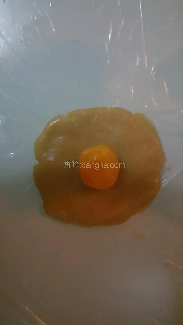 取一个莲蓉剂子按成饼，放入鸭蛋黄。