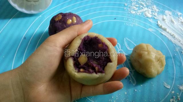 将月饼皮压成薄饼，包住馅料，然后慢慢收紧封口。