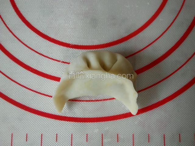 先对折饺子皮，将中间捏紧，一个一个的褶子捏，一层叠一层