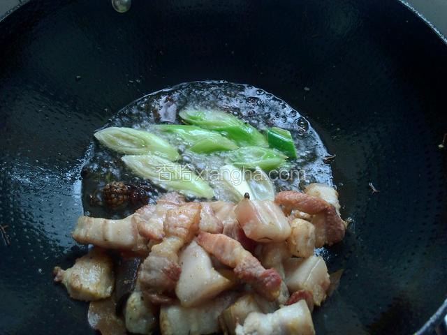 等五花肉炒出猪油，放入葱段煸炒