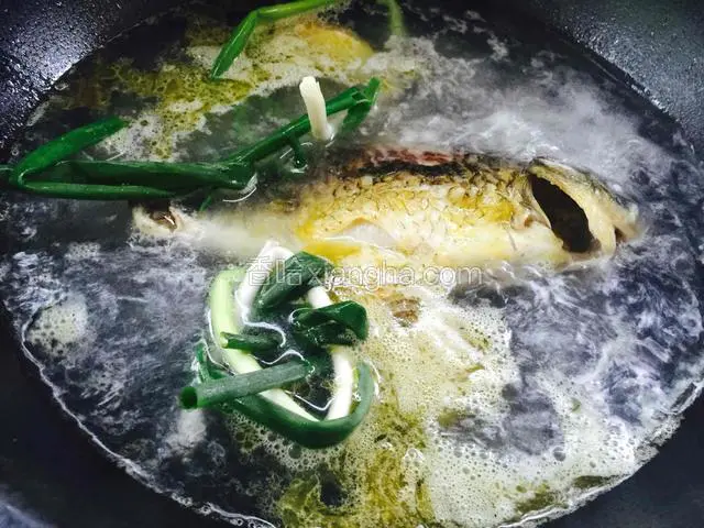 鱼煎好后给锅里倒入开水，开水量没过鲫鱼就可以了，放入葱结和姜片，关小火，盖上锅盖炖一个小时左右。