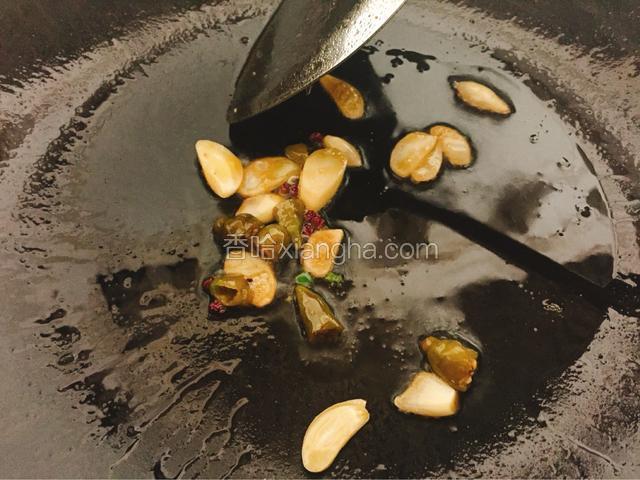 接着，锅内再倒入少许食用油，放入蒜片，花椒，野山椒爆香。