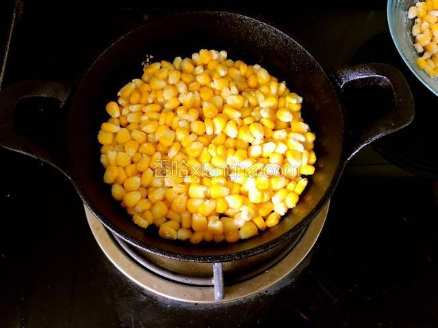 锅中倒入油。油热后放入玉米，平铺压平。