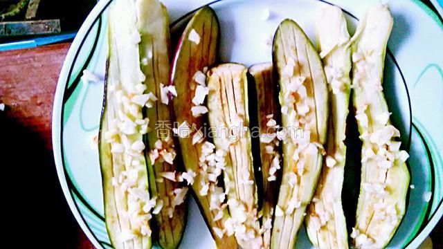 把腌制好的茄子冲洗去盐水刷上油，撒上大蒜末，盖上保鲜膜上微波炉先中火烤三分钟。