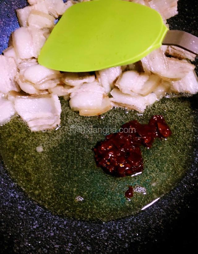 肉片逼出油分变得卷翘将肉片拨到一边放入豆瓣酱炒香后与肉片炒均匀