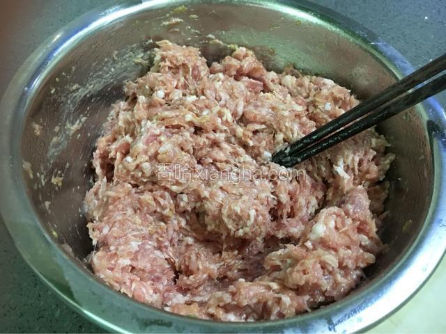 用筷子朝一个方向将肉馅搅拌上劲。