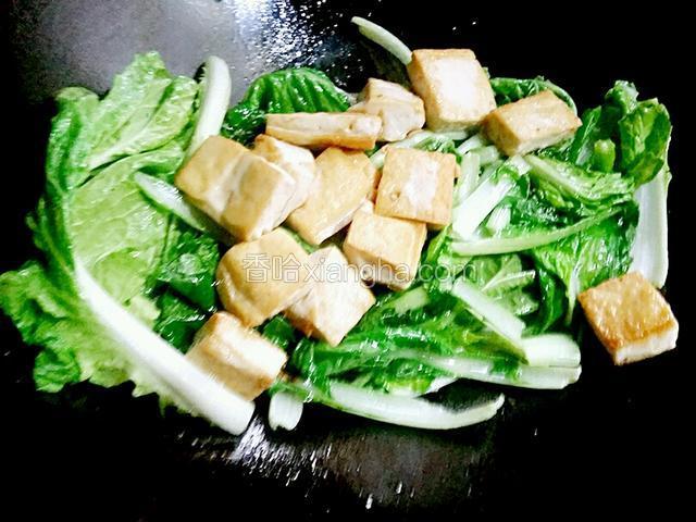 把煎好的豆腐下锅，调中火翻锅炒制一分钟，用锅铲炒，要注意不要把豆腐炒烂了，这样影响美观