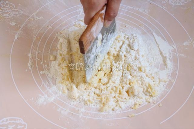 先制作酥皮部分。糖粉面粉混合过筛至操作台上。将冷藏黄油放在粉上，用刀切碎至无大颗粒。