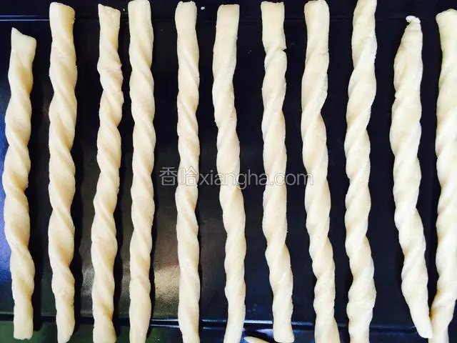 把擀好的面片用刀切成一条一条的长条，两手拿起两端扭几圈，再放到烤盘上即可，烤盘不用抹油。