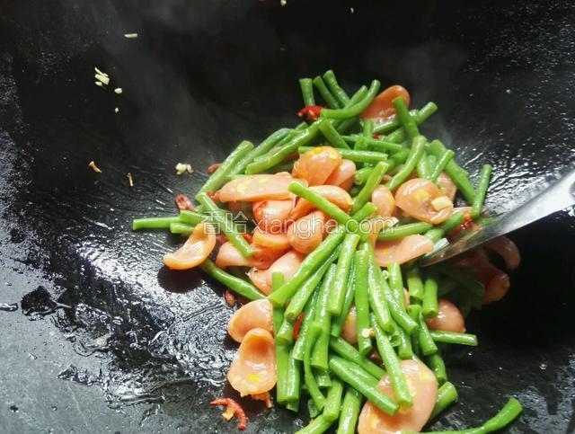 倒入淖过水的豆角和红尖椒，调入适量盐和鸡精洒适量清水，迅速翻炒即可出锅